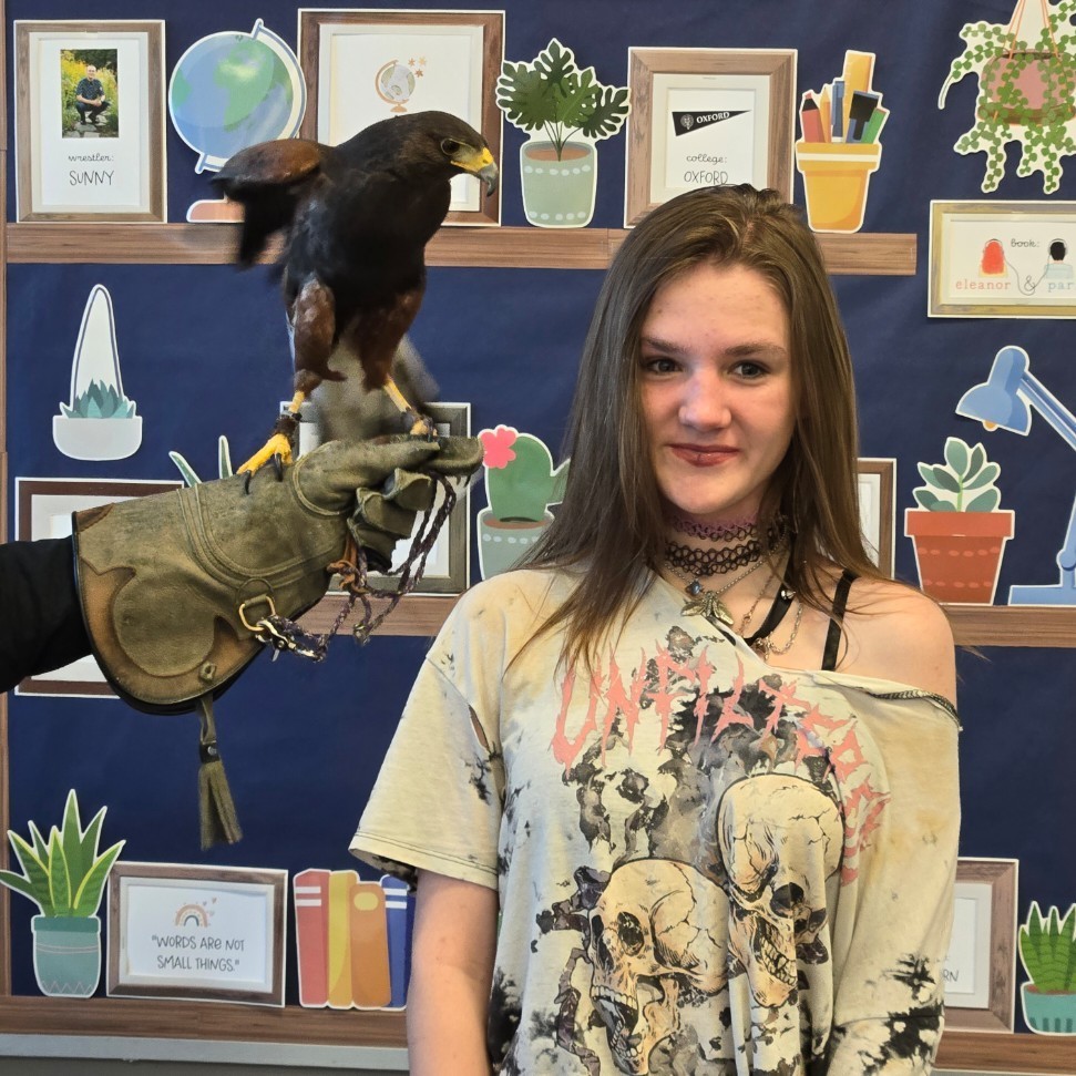 A female student posing with a harris hawk
