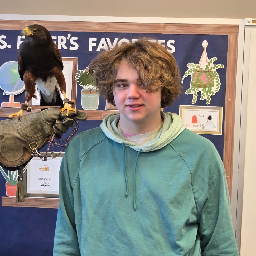 A student posing with a harris hawk