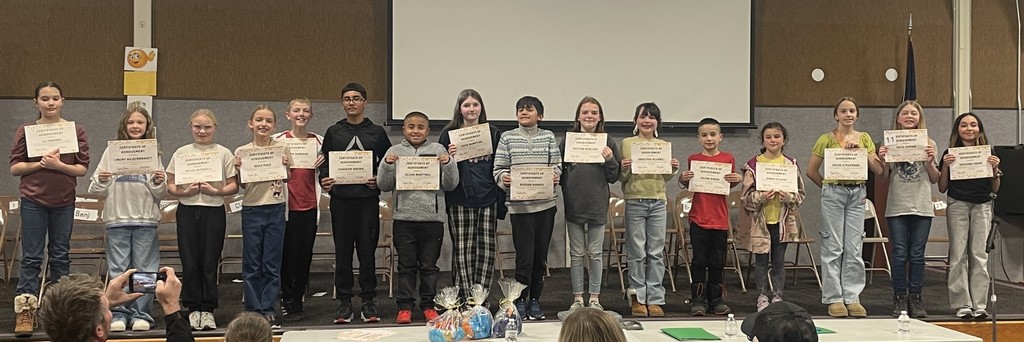 students stand with their certificates for participating in the school spelling bee
