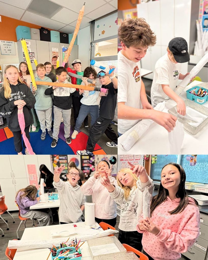 A group of sixth grade students in the art room holding large, colorful paper-mâché art supplies. Other students dip paper into paste and wrap it around forms to build the sculptures.