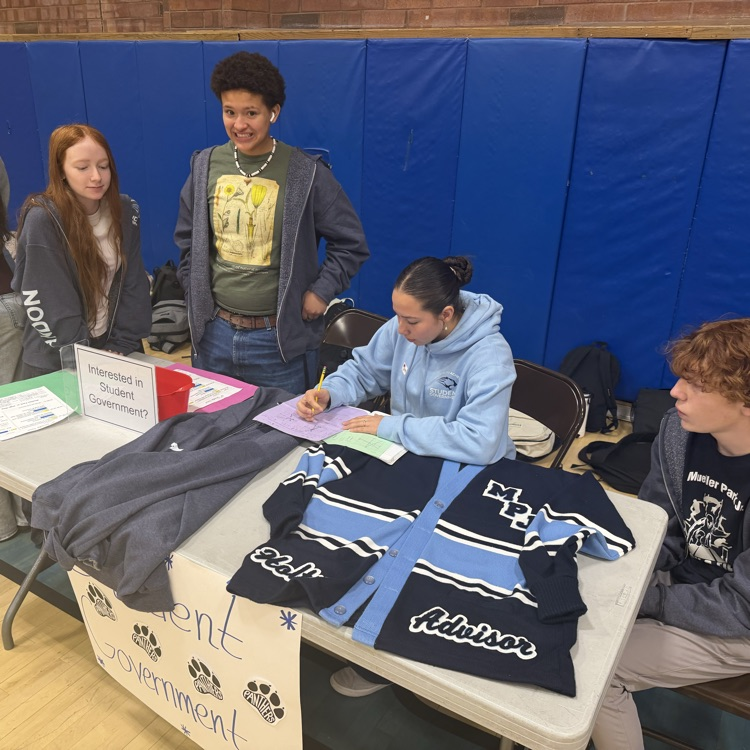 student government officers sit at a table talking about being an SBO to the incoming 7th graders
