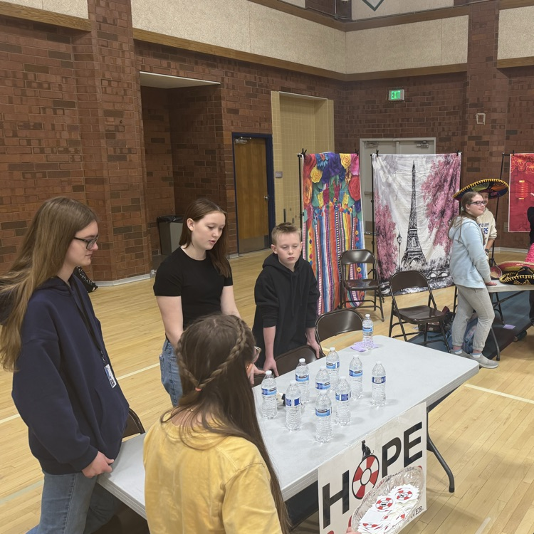 students sit at the hope squad table explaining to a student about hope squad.