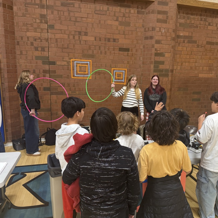 students are lined up waiting to throw things into some colorful hoops