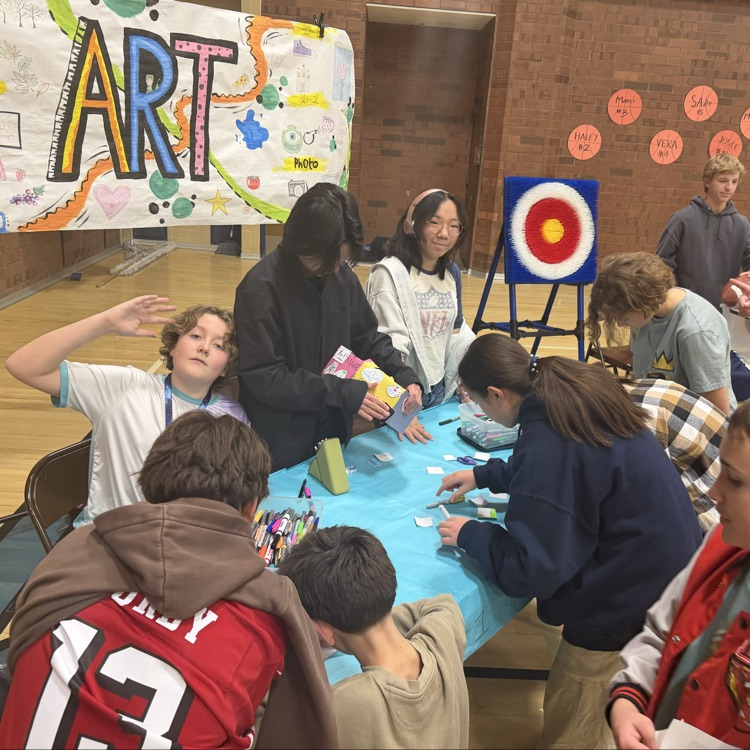 a group of students sit at the art table doing some fun art projects