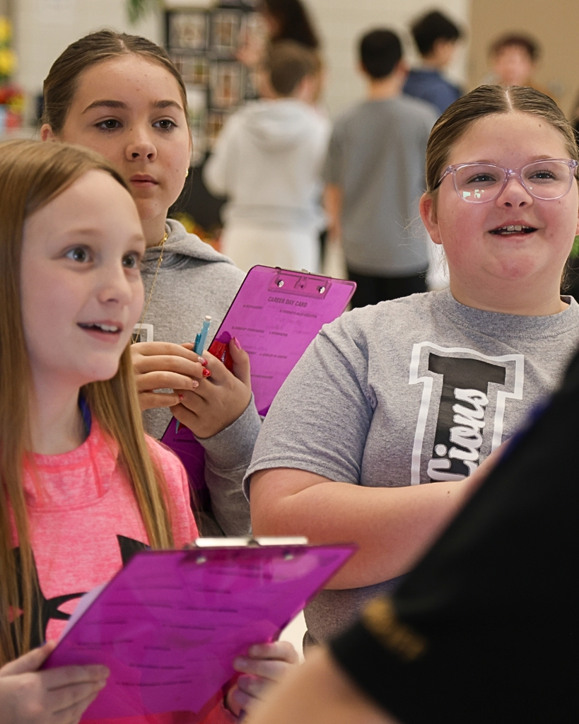 Students smiling holding clip boards. 