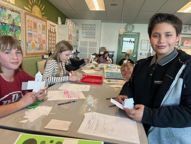a boy and girl smiling while holding paper in their hands