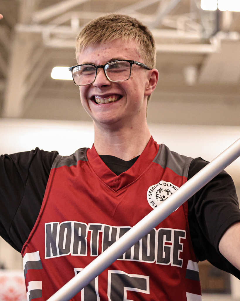 A Northridge High student smiles as he holds his school's flag during the Special Olympics Unified Basketball March of Athletes.