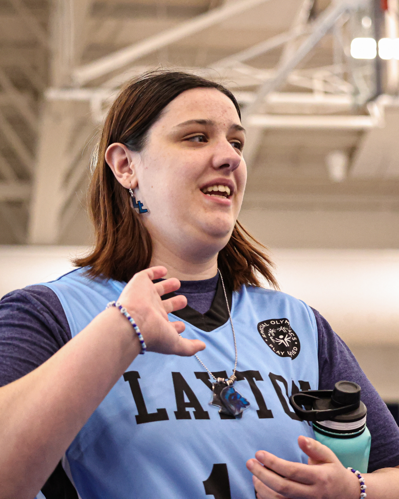 A Layton High athlete smiles to the right and waves. 