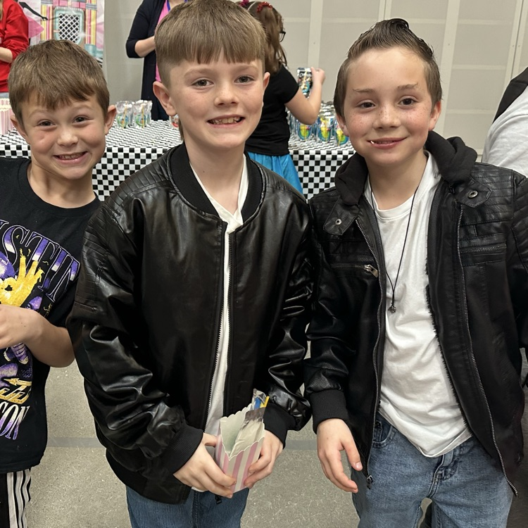 three boys in leather jackets smiling with popcorn