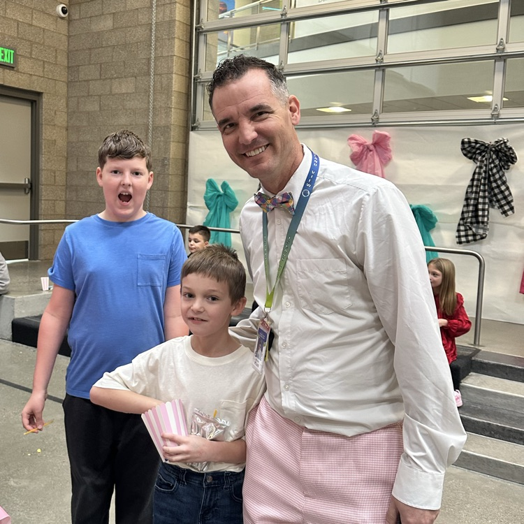 two boys eating popcorn and a man in pink pants