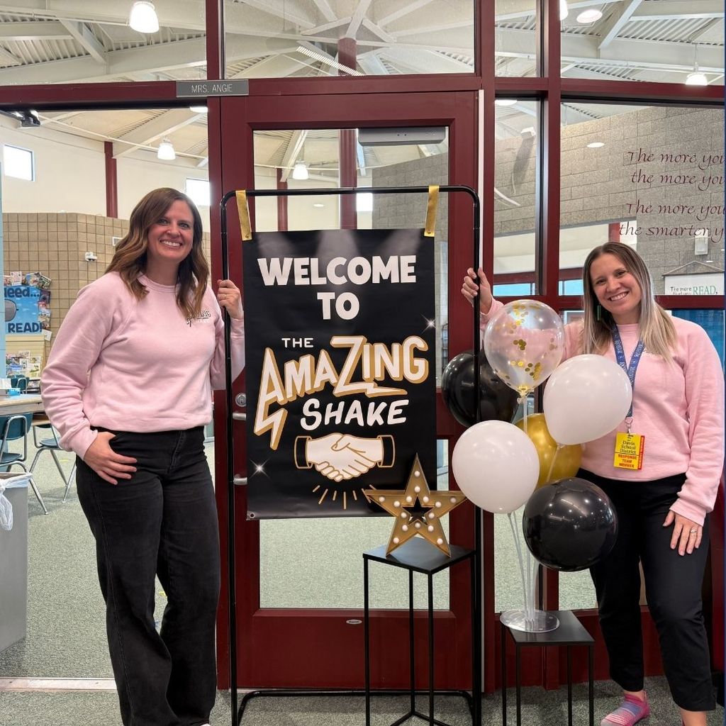 Teachers posing by a sign the reads Welcome to the Amazing Shake.