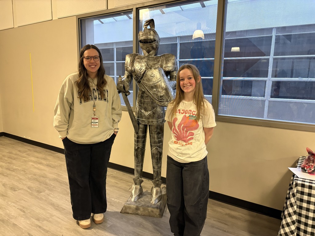image of a student and teacher standing in front of a knight statue