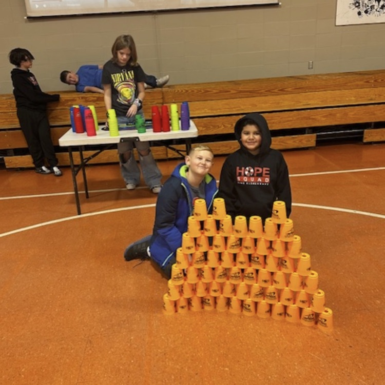 students practicing cup stacking speed drills and working together as teams during PE