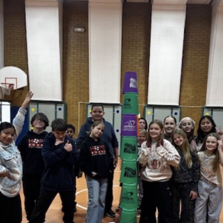 students practicing cup stacking speed drills and working together as teams during PE