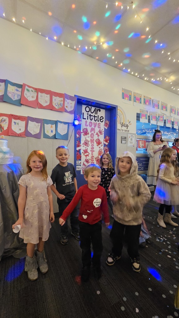 students smiling with confetti and a monsters sign behind