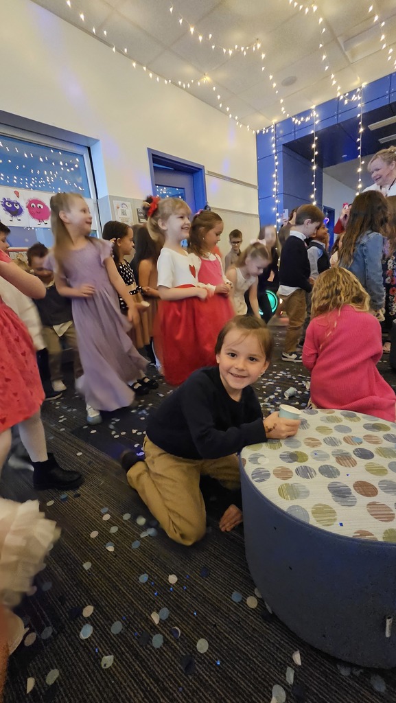 student picking up confetti while other students smile and all are dressed nicely