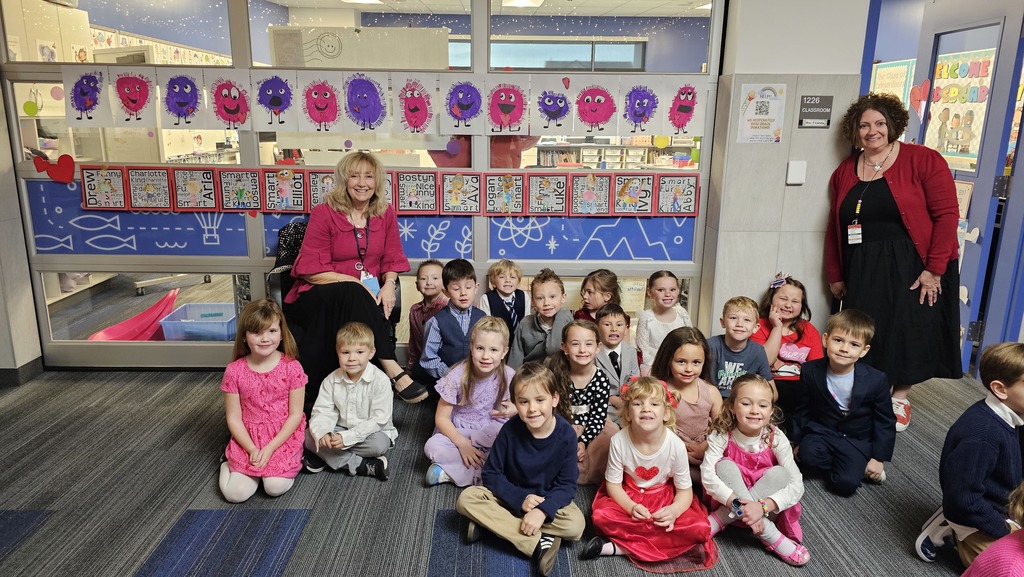 two women with group of students dressed in nice clothes sitting on ground