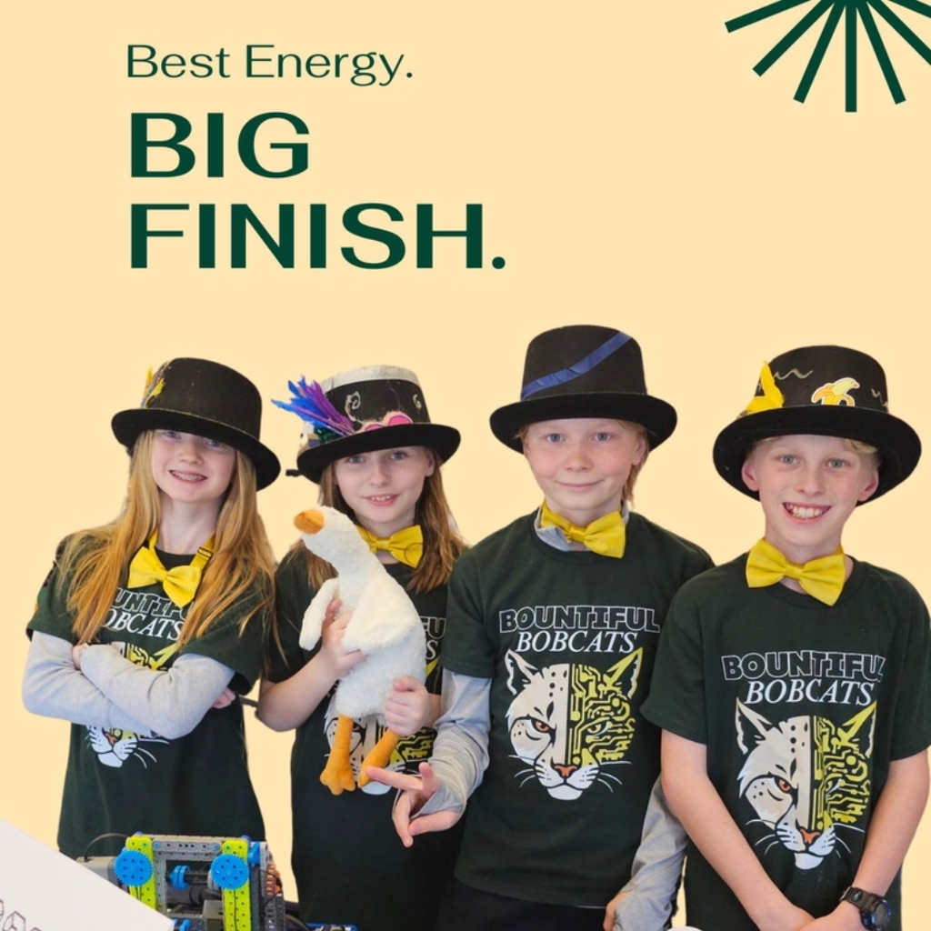 Four students in matching dark green Bountiful Bobcats shirts wear black hats and yellow bow ties, standing behind a table with a VEX robot and controller; one student holds a stuffed goose. Text reads “Best Energy. BIG FINISH.” Bountiful Elementary logo in the bottom left.