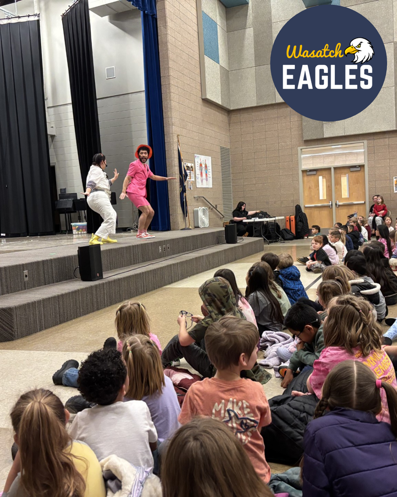 Students watching an acting performance with 2 people on the stage.