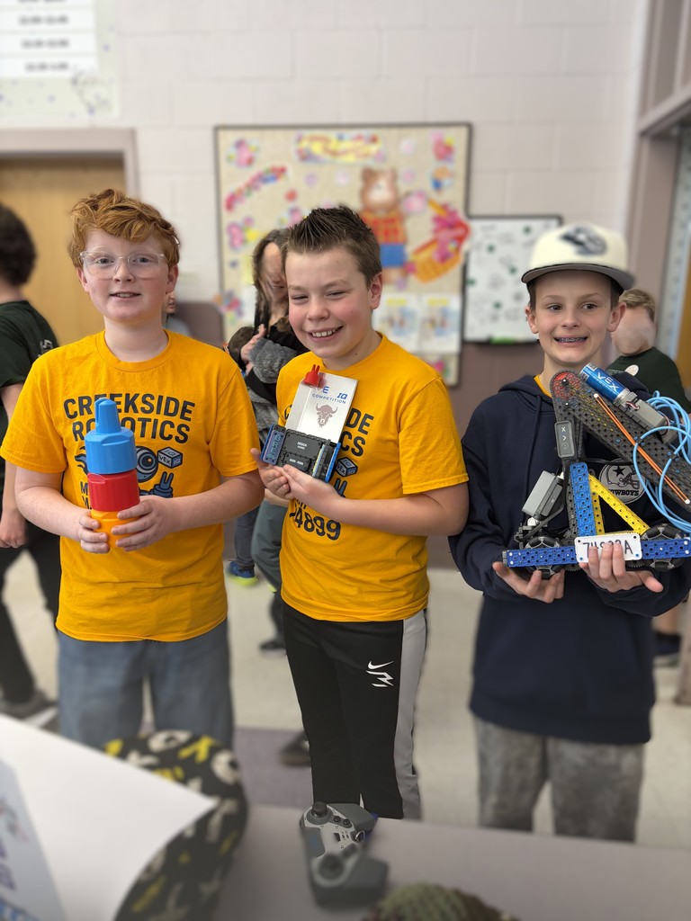 three boys holding trophy and robot at the robotics competition 