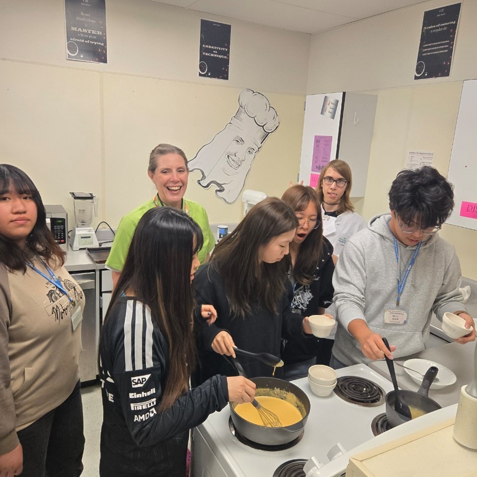 Mrs. Nettleship helping the taiwanese exchange students with a cooking experience of mac and cheese