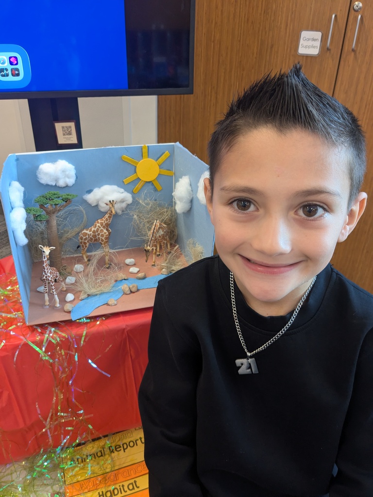2nd Grader posing next to animal diorama. 
