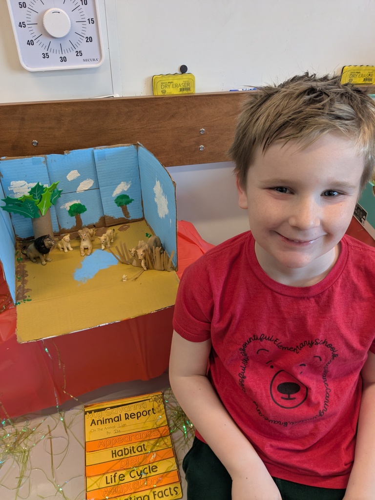 2nd Grader posing next to animal diorama. 