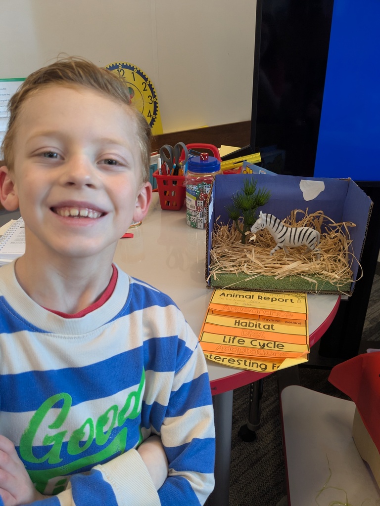 2nd Grader posing next to animal diorama. 