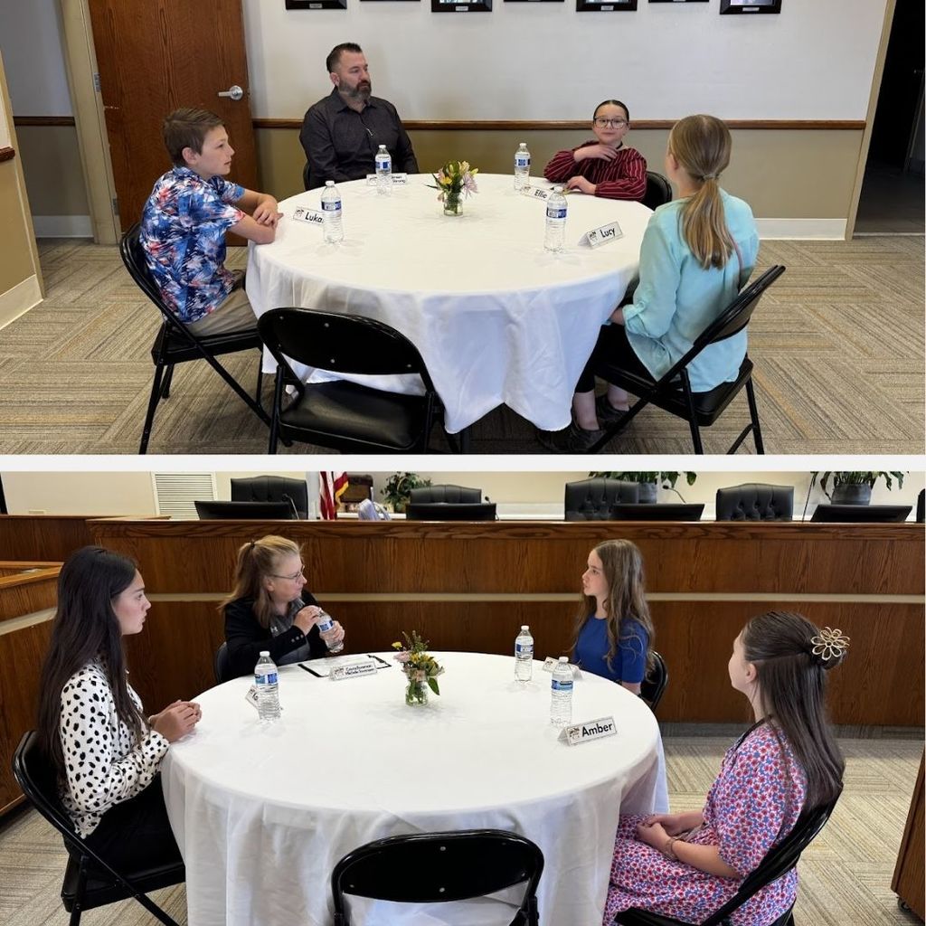 Students eating food and having a discussion at a round table with city leaders.