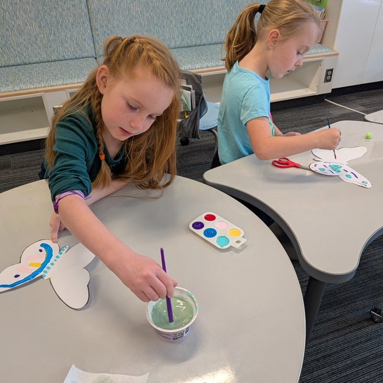 two girls painting butterfly papers