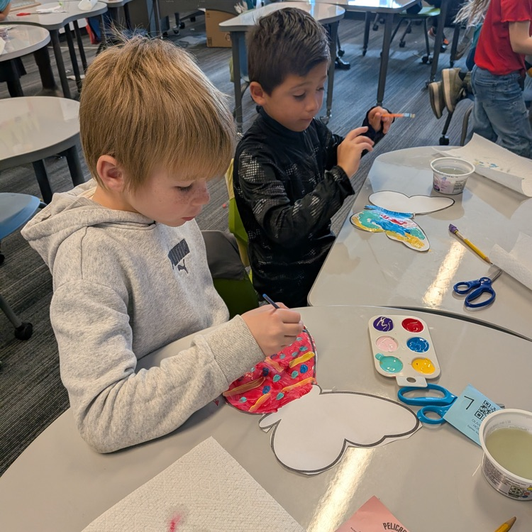 two boys painting butterflies with red wings and polka dots