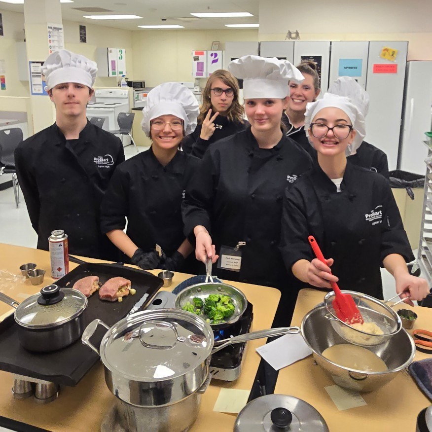 Mrs. Nettleship and the Prostart students posing by their food