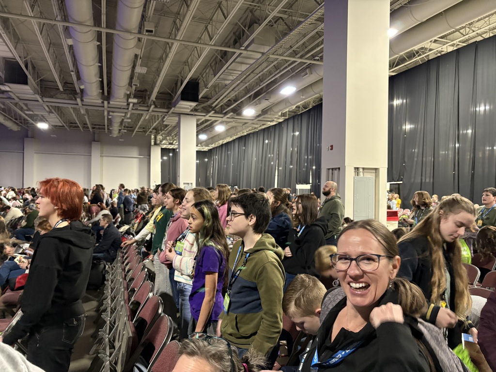 Several students gathered at StoryCon with dozens of other students in the background. 