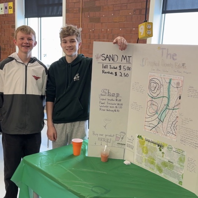 two male students stand in front of their poster, presenting about environmental AP science