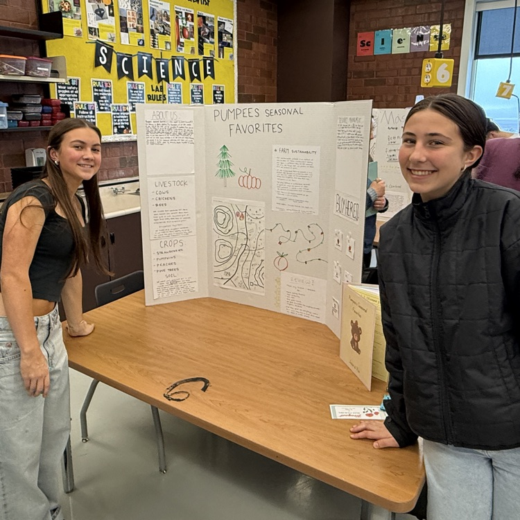 two female students stand in front of their poster for AP environmental science