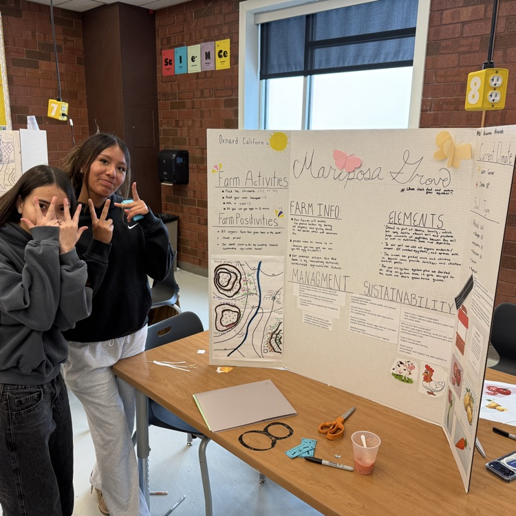 two female students stand in front of their poster for AP environmental science