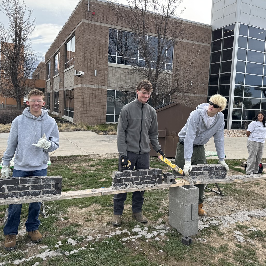 students learn how to use mortar to lay bricks
