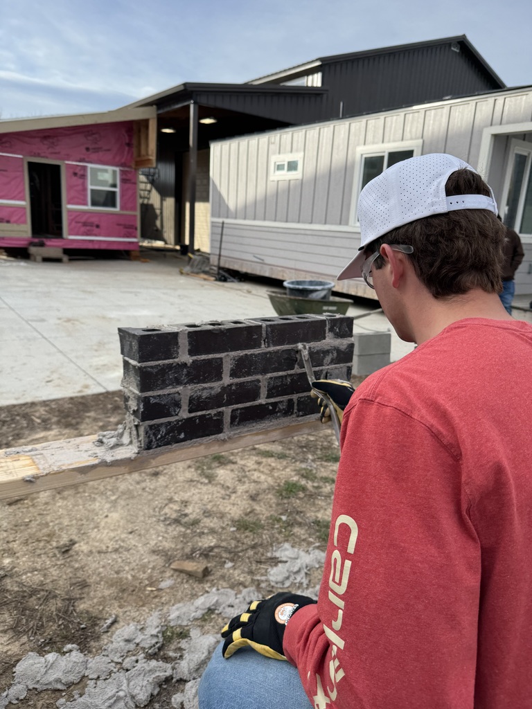students learn how to use mortar to lay bricks