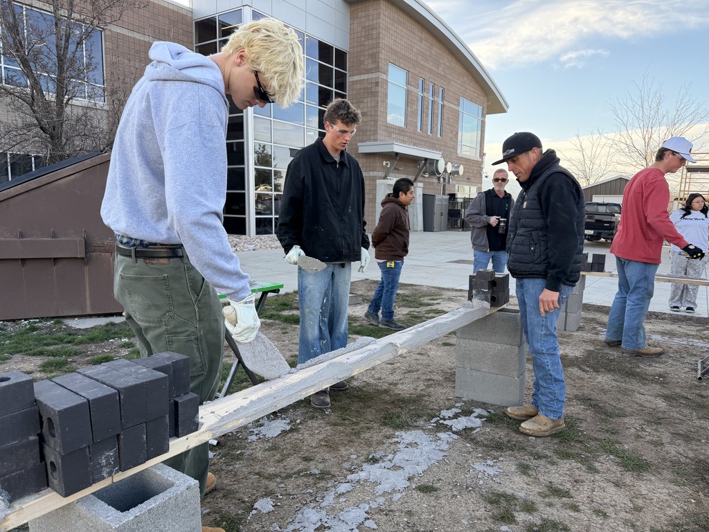 students learn how to use mortar to lay bricks