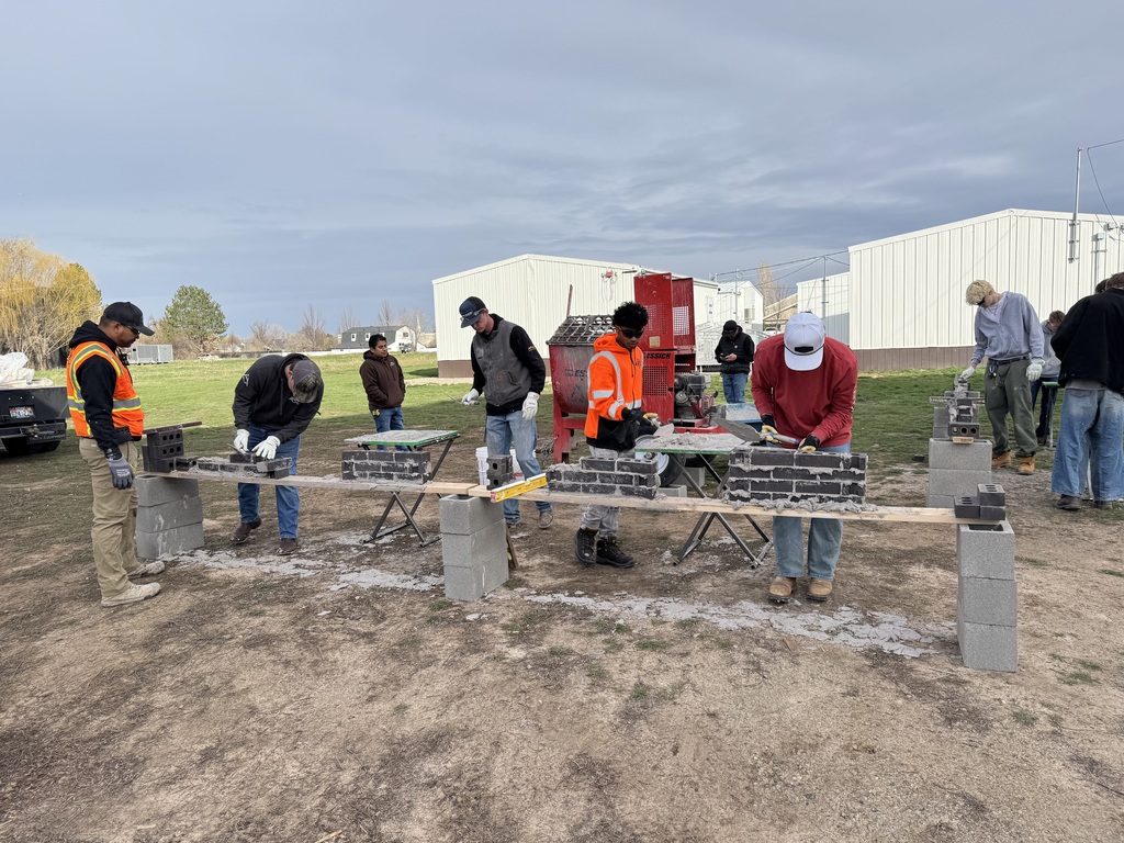 students learn how to use mortar to lay bricks