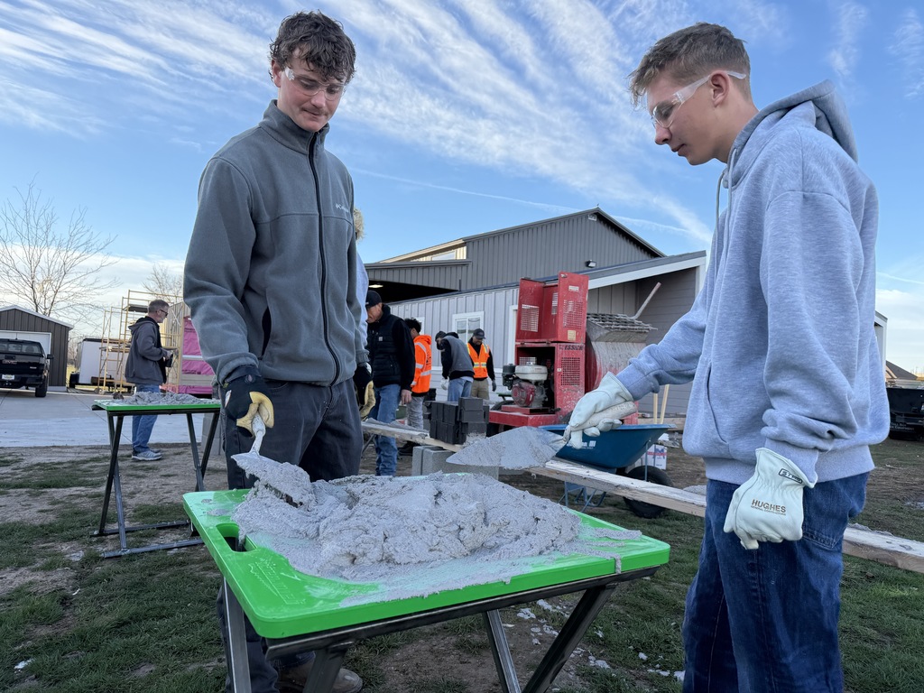 students learn how to use mortar to lay bricks