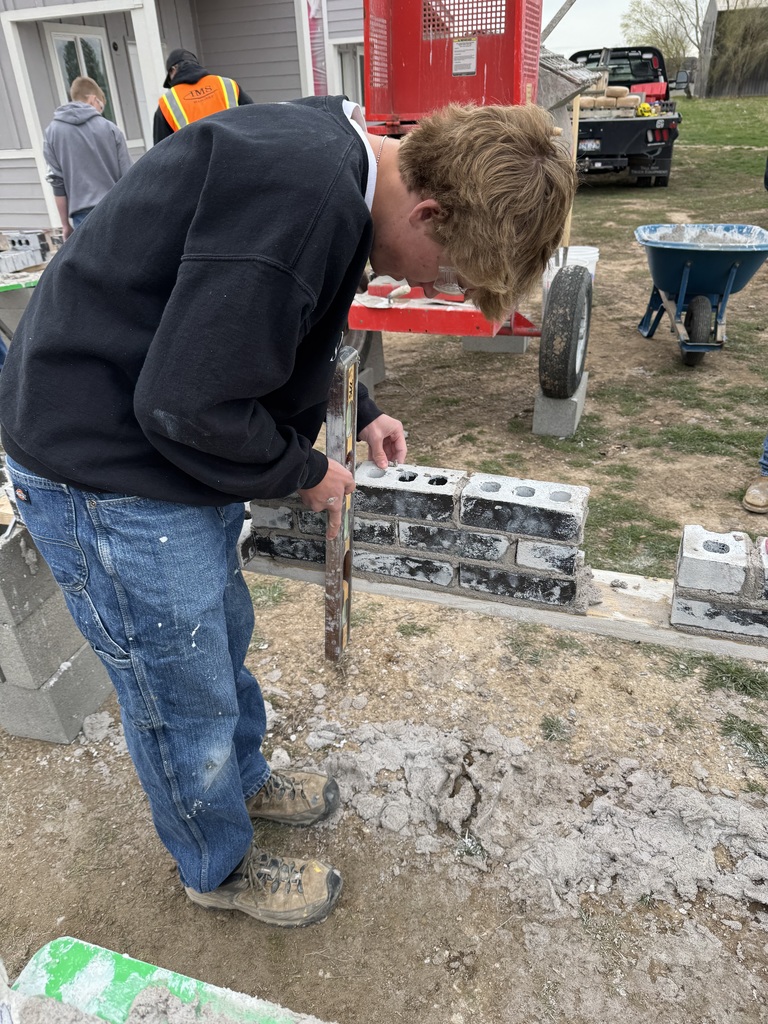 students learn how to use mortar to lay bricks