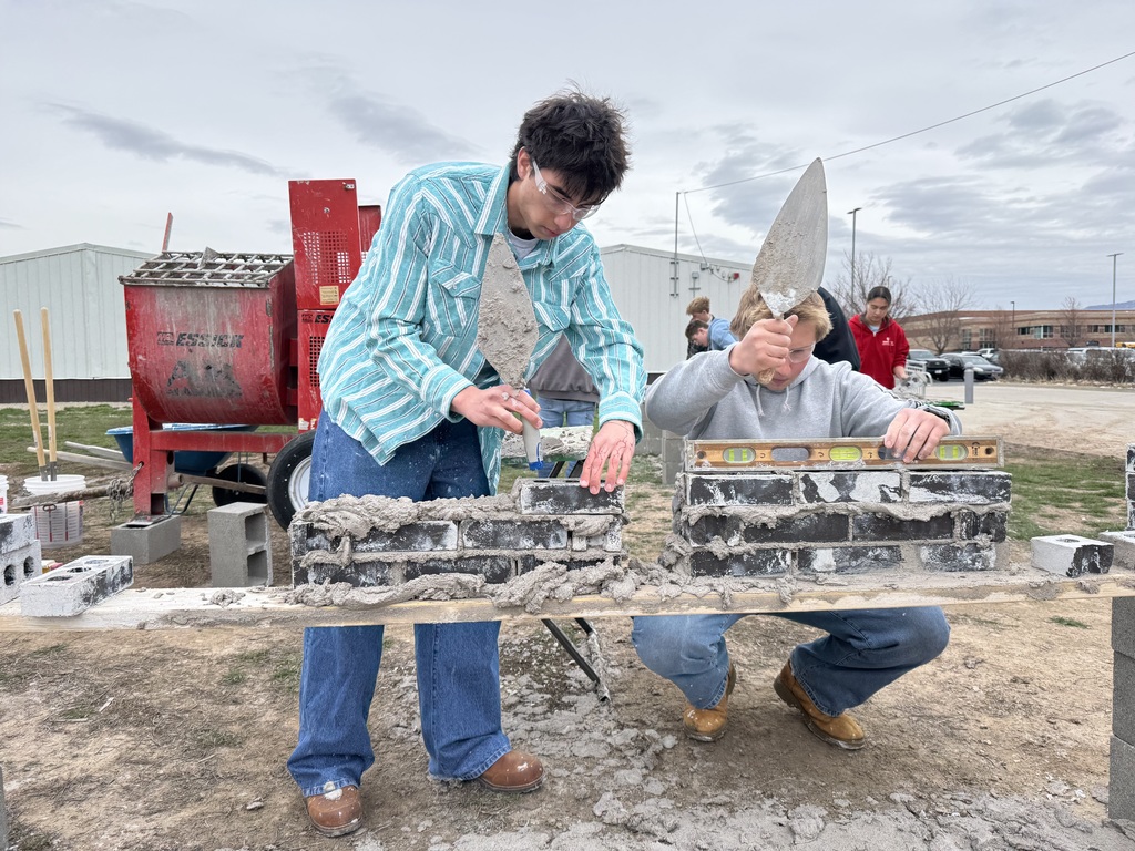 students learn how to use mortar to lay bricks