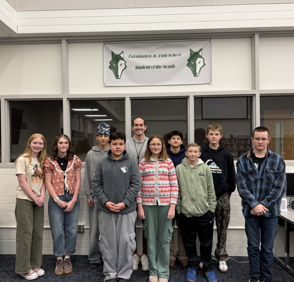 FJH students selected to be March Students’ of the Month with an educator who was also selected. They are standing underneath a student of the month banner in the library. 