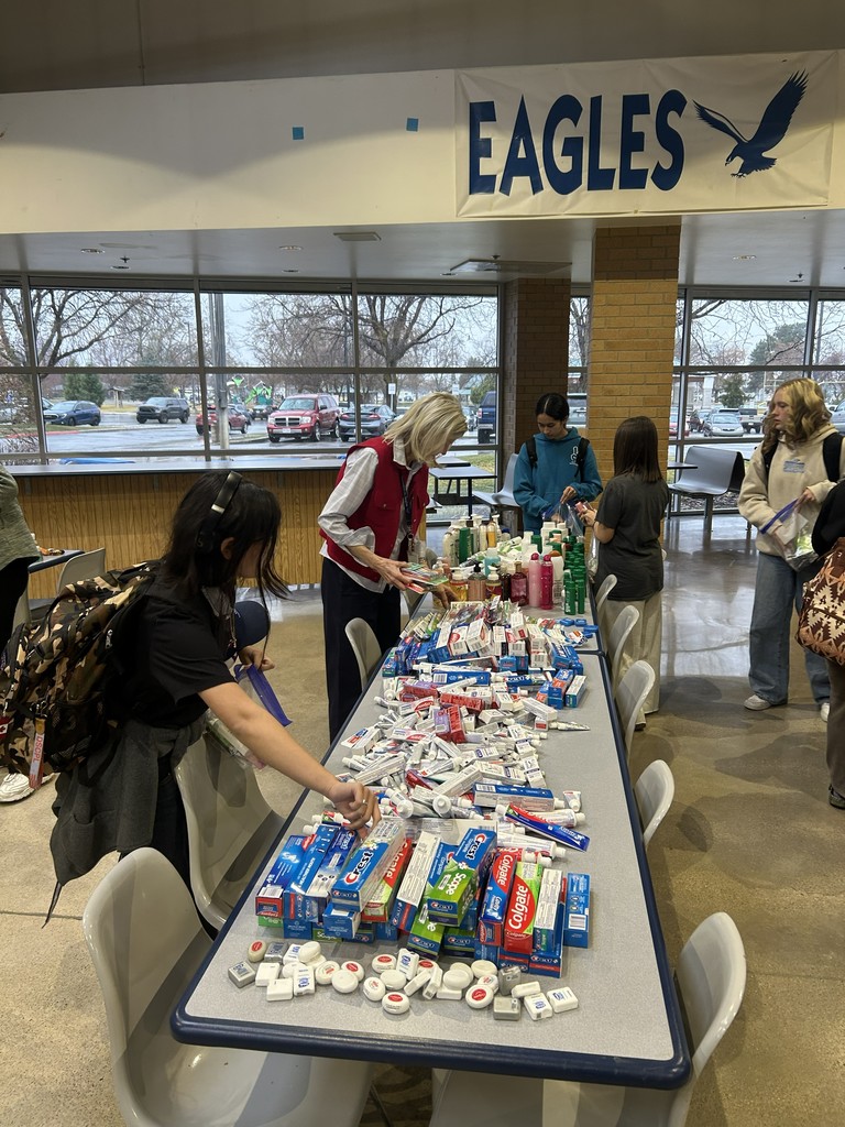 Students assembling hygiene kits including floss, toothpaste, toothbrushes. 