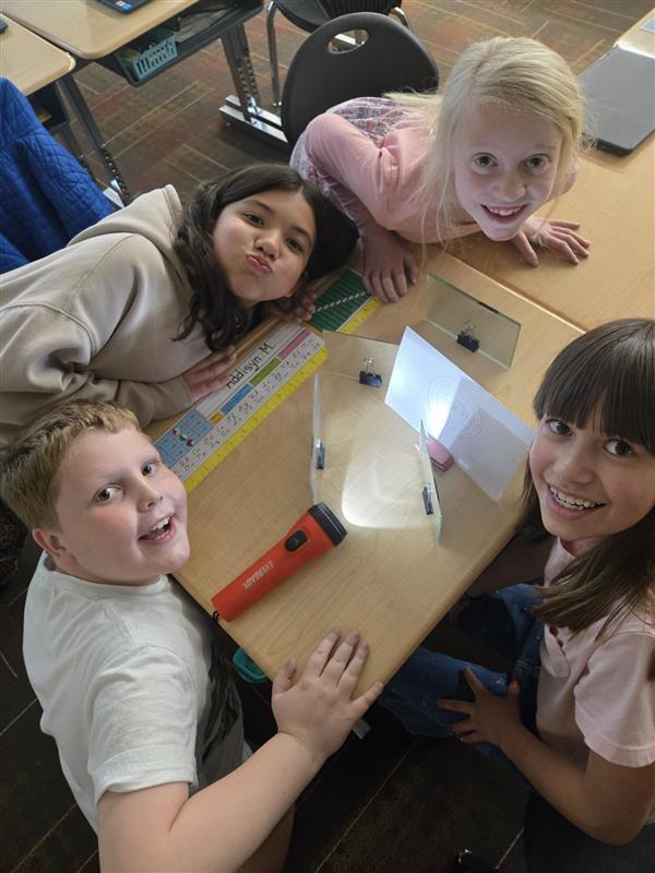 group of 4 students with flashlights and mirrors