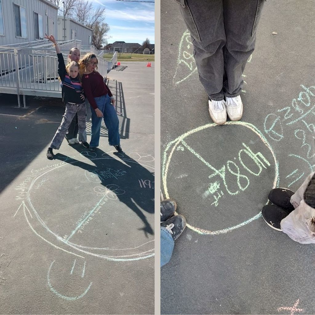 Students drawing circles on the pavement with chalk.