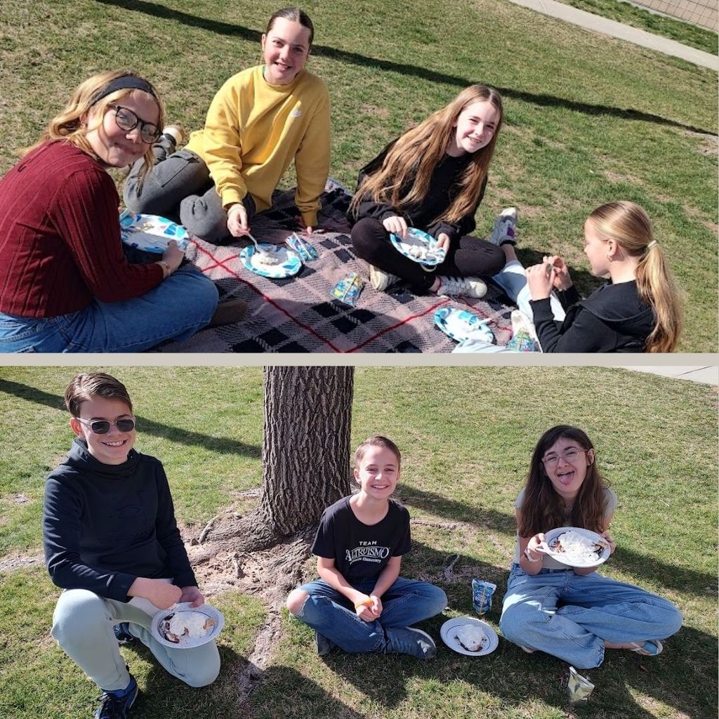 Students sitting outside eating pie.
