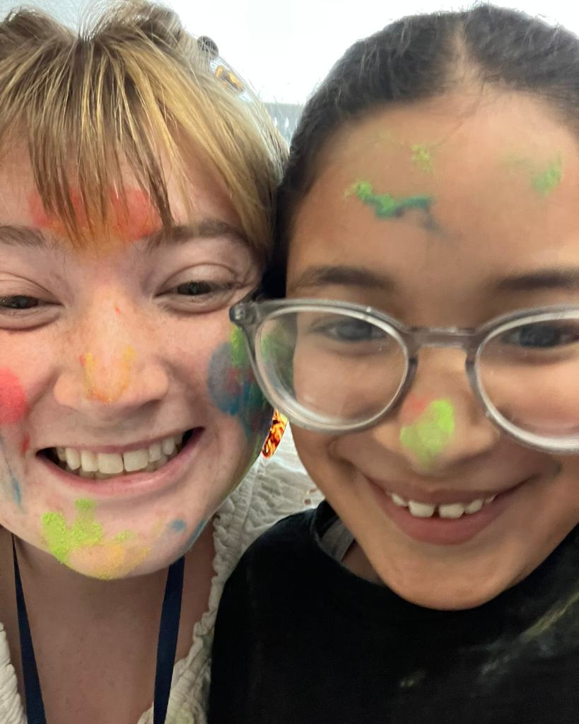 A  student with a colorful face smiles at the camera. 
