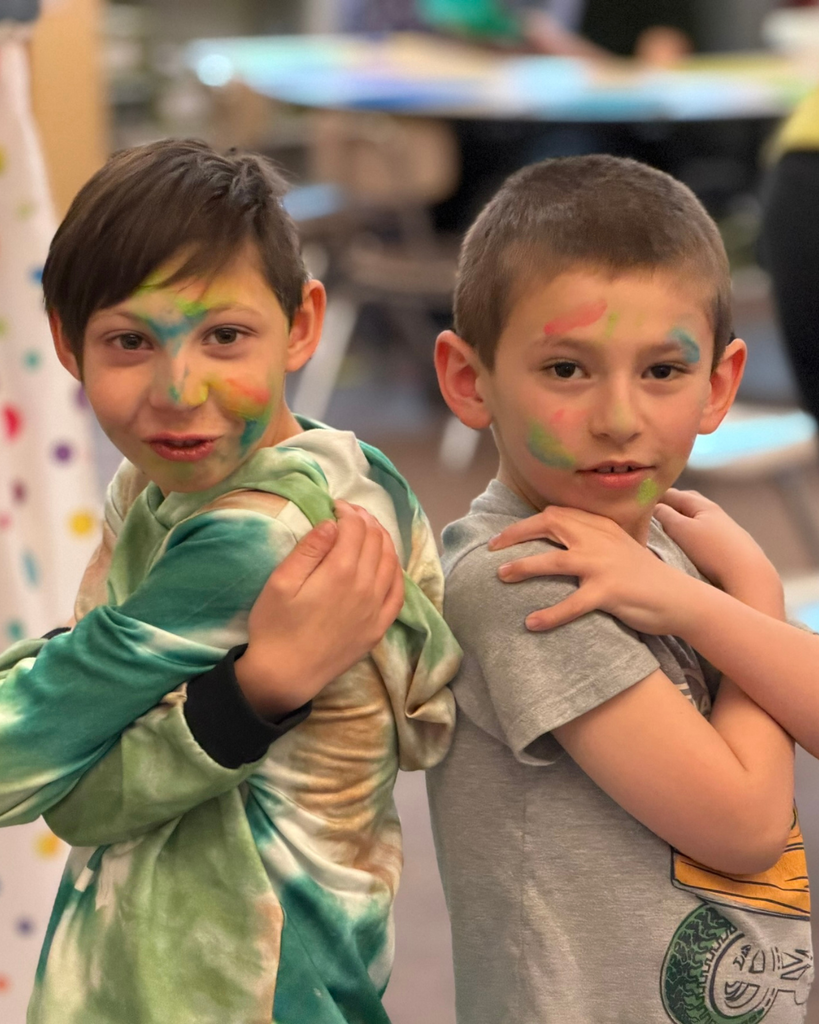 A  student with a colorful face smiles at the camera. 